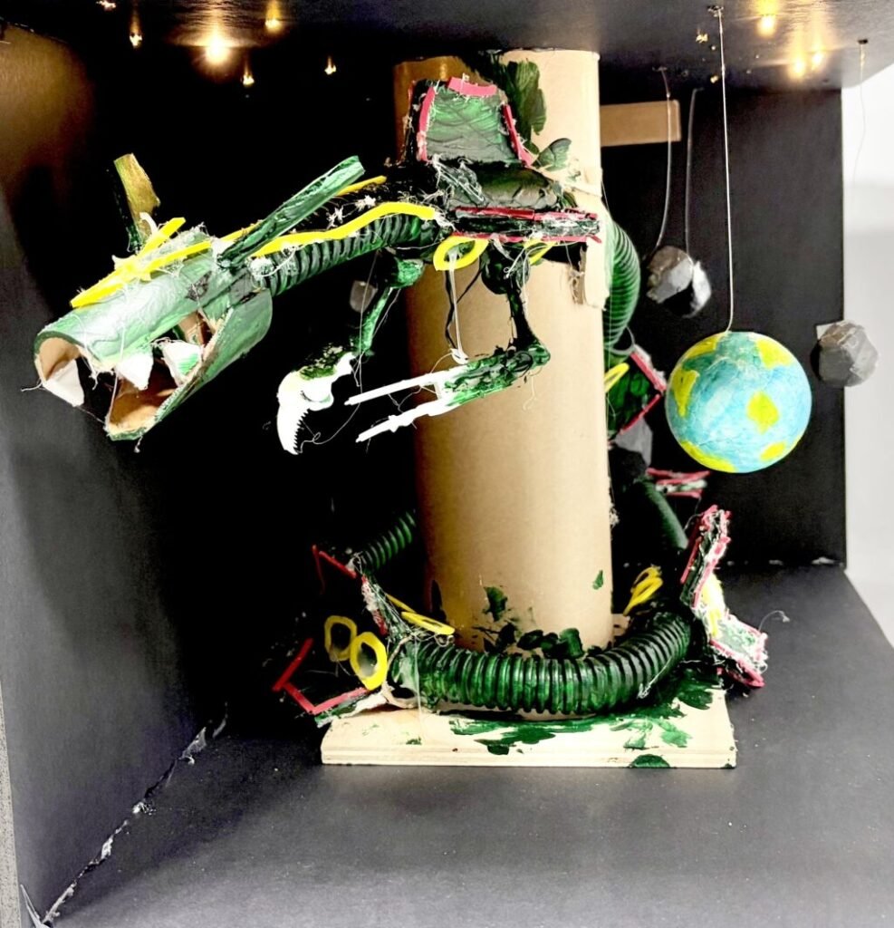 A 3D art project created by a young boy, featuring the Pokemon Rayquaza inside a cardboard space diorama with planets hanging on strings. A masterpiece from a specialized boys' art lab in Korea.
